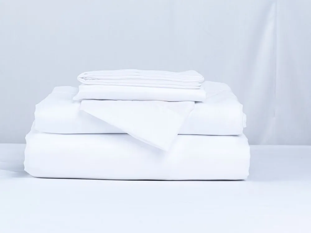 Pile de linge de lit blanc propre, soigneusement plié